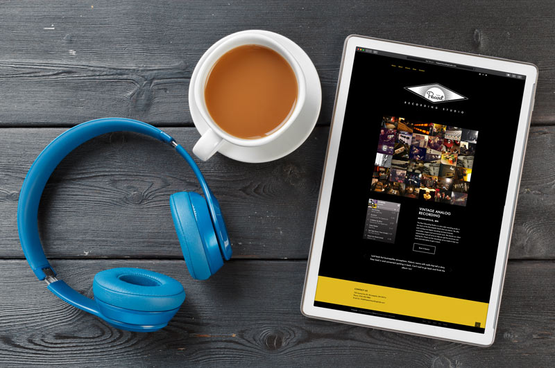 recording studio website on tablet next to headphones and coffee mug