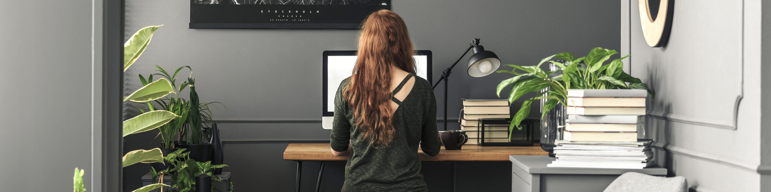 woman writing on a desktop computer sitting at a desk